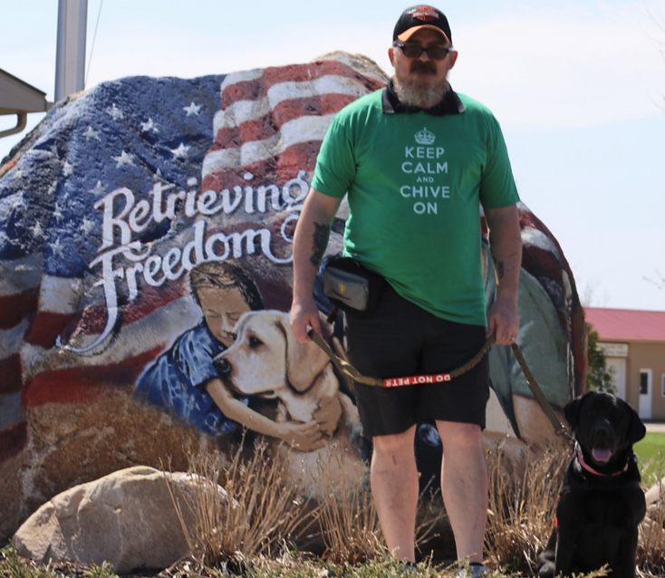 Ty Buras and his service dog, Wrigley, pose outside of the Retrieving Freedom organization.